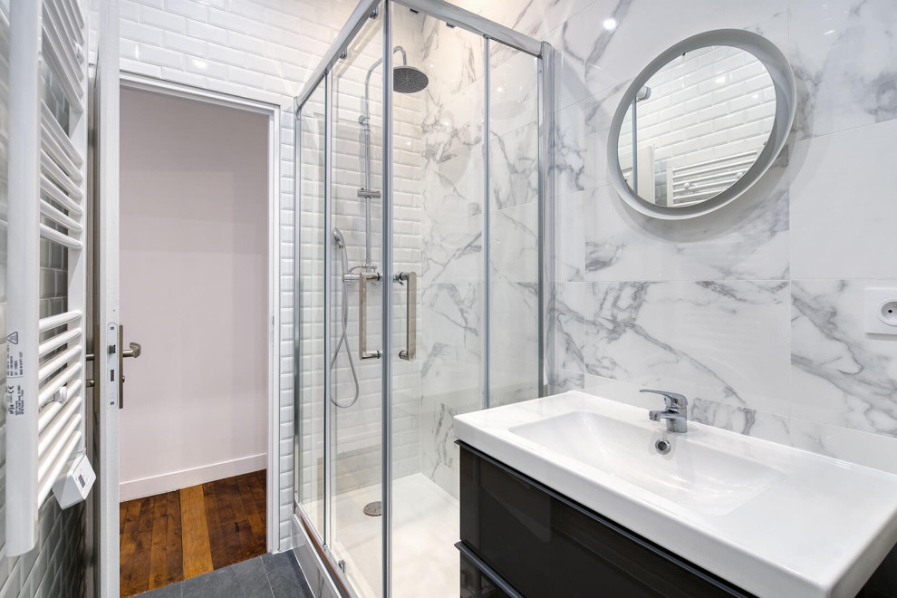 Photo of a small contemporary shower room bathroom in Lyon with beaded cabinets, black cabinets, a corner shower, a wall mounted toilet, black and white tiles, marble tiles, white walls, ceramic flooring, a trough sink, grey floors, a sliding door, a single sink and a floating vanity unit.