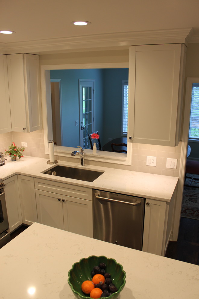 Inspiration for a mid-sized transitional l-shaped dark wood floor and brown floor enclosed kitchen remodel in Chicago with an undermount sink, recessed-panel cabinets, white cabinets, quartzite countertops, white backsplash, subway tile backsplash, stainless steel appliances and an island