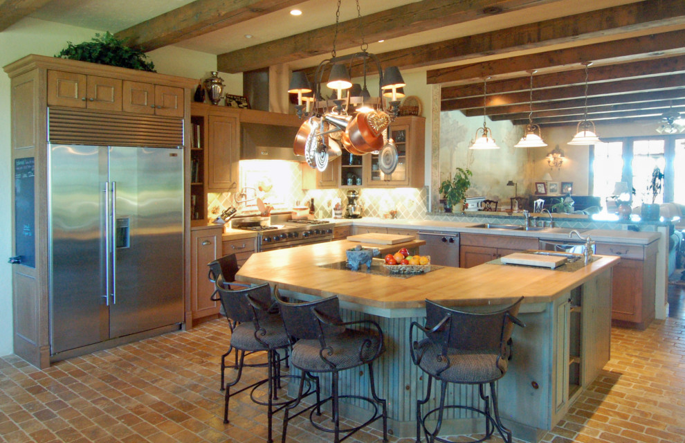 Large mediterranean u-shaped open plan kitchen in San Luis Obispo with a triple-bowl sink, recessed-panel cabinets, green splashback, ceramic splashback, stainless steel appliances, brick floors, with island, orange floor, exposed beam, green cabinets and wood benchtops.