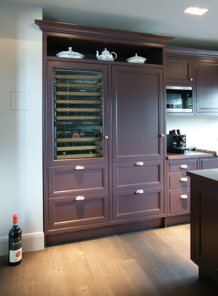 Photo of a country open plan kitchen in Hamburg with a farmhouse sink, beaded inset cabinets, purple cabinets, quartz benchtops, white splashback, glass sheet splashback, black appliances, dark hardwood floors and with island.
