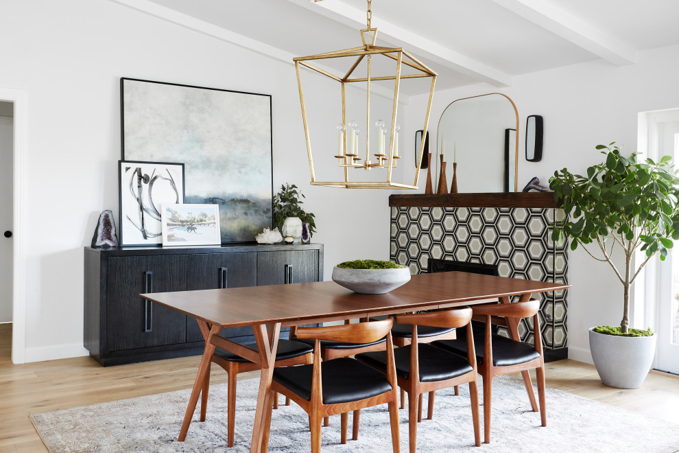 This is an example of a scandinavian dining room in Los Angeles with white walls, light hardwood floors, a standard fireplace, a tile fireplace surround and vaulted.