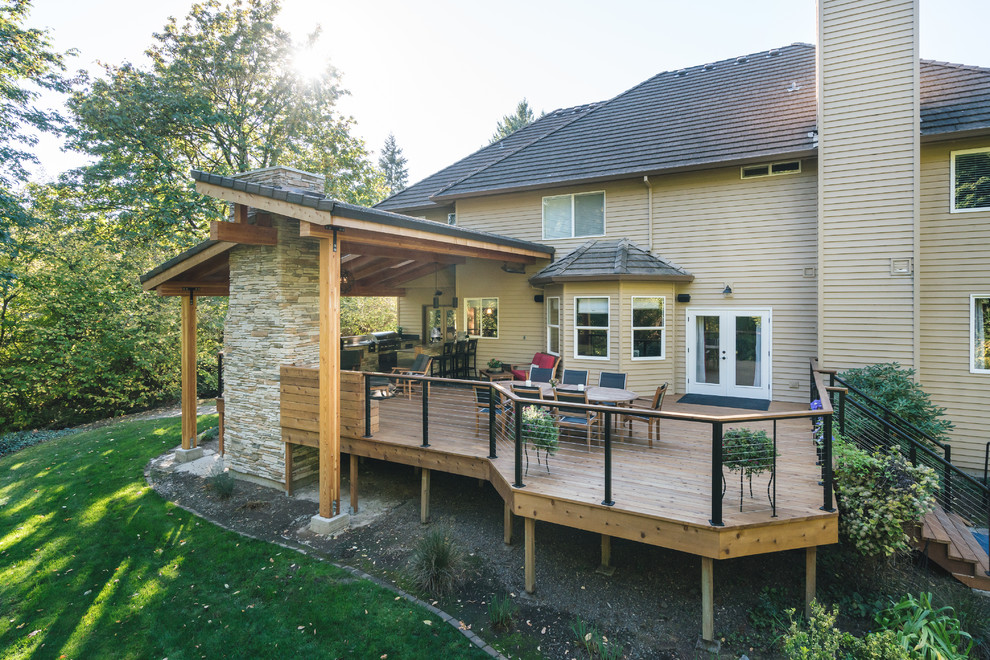 Large contemporary deck in Portland with an outdoor kitchen and a roof extension.