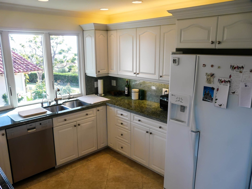 This is an example of a mid-sized modern u-shaped open plan kitchen in San Diego with an undermount sink, raised-panel cabinets, white cabinets, granite benchtops, stone slab splashback, white appliances, porcelain floors and a peninsula.