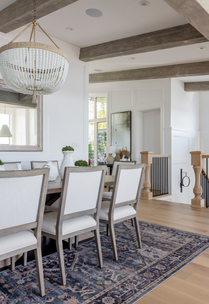 Coastal open plan dining room in Vancouver with white walls, light hardwood flooring, beige floors, exposed beams and wainscoting.