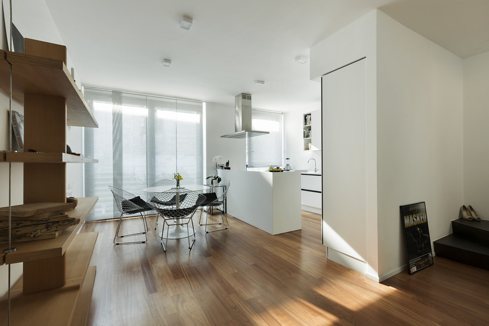 Photo of a mid-sized contemporary u-shaped eat-in kitchen in Milan with quartz benchtops, light hardwood floors, with island, beige floor, white benchtop, white cabinets, an integrated sink, flat-panel cabinets and panelled appliances.