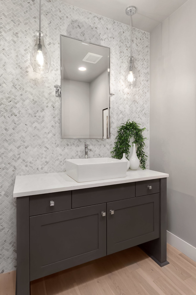 Inspiration for a large contemporary powder room in Seattle with shaker cabinets, a one-piece toilet, light hardwood floors, a vessel sink, engineered quartz benchtops and white benchtops.