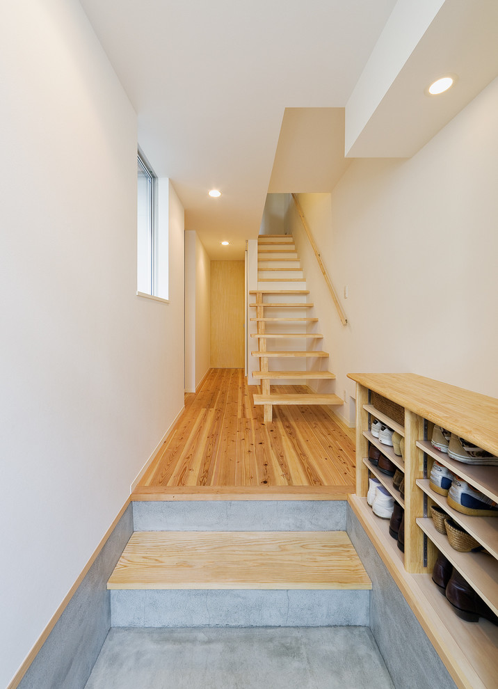 This is an example of a scandinavian entryway in Osaka with white walls, concrete floors and grey floor.