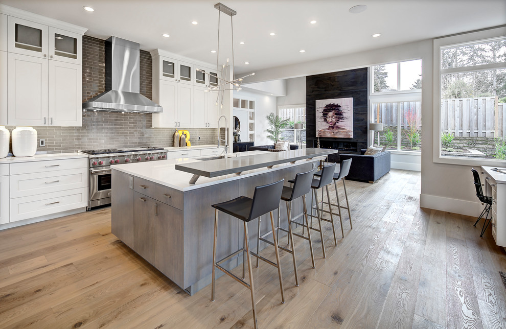 Inspiration for a contemporary galley open plan kitchen in Seattle with an undermount sink, flat-panel cabinets, grey cabinets, brown splashback, stainless steel appliances, light hardwood floors, with island, beige floor and white benchtop.