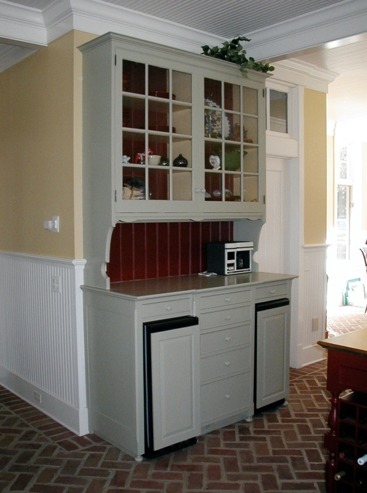 This is an example of a large traditional galley eat-in kitchen in Other with a farmhouse sink, raised-panel cabinets, grey cabinets, soapstone benchtops, black splashback, stone slab splashback, stainless steel appliances, brick floors, with island and red floor.