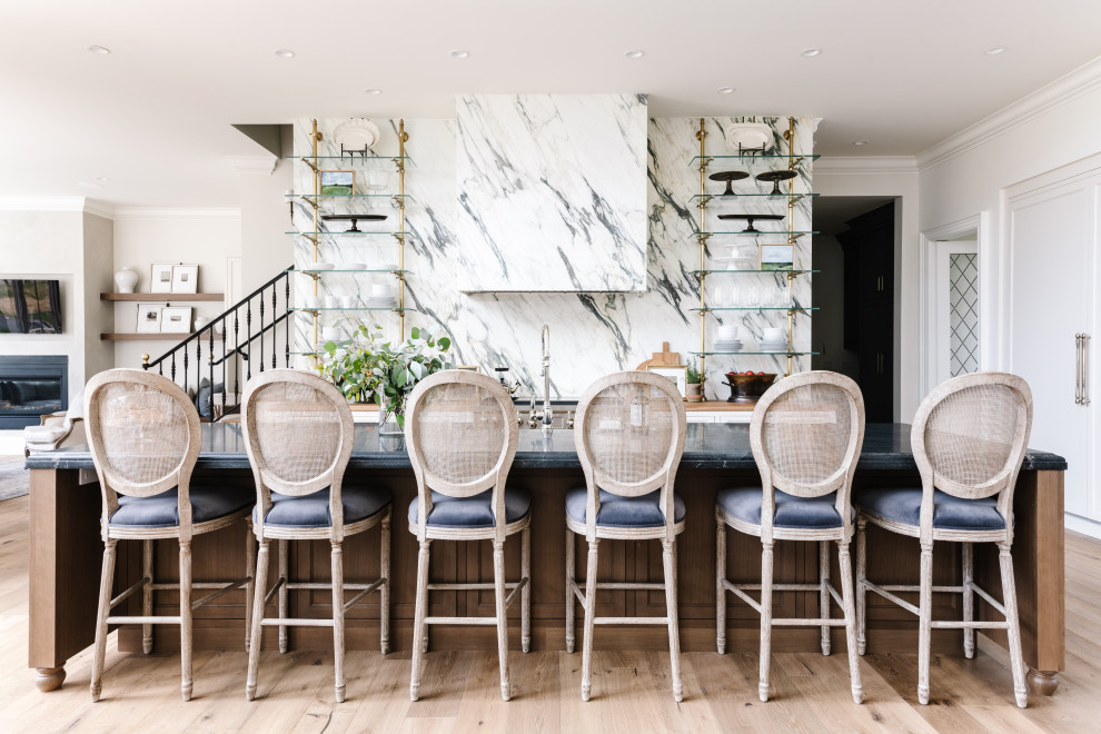 Elegant light wood floor kitchen photo in Salt Lake City with shaker cabinets, white cabinets, stainless steel appliances, an island and black countertops
