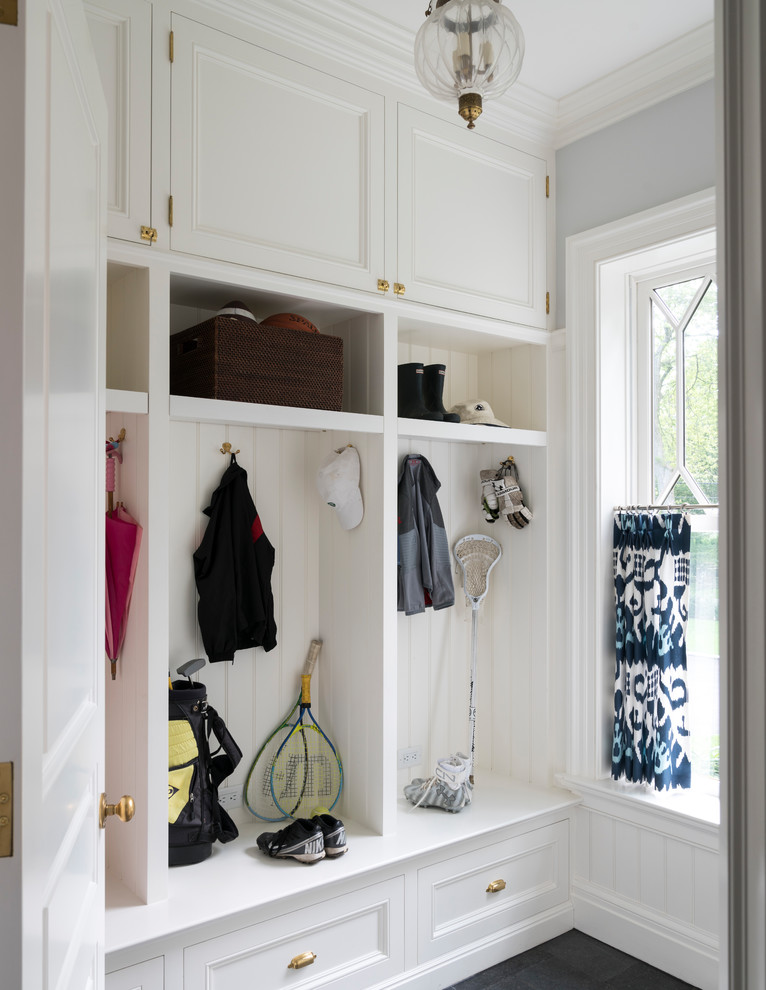 Large beach style gender-neutral walk-in wardrobe in New York with recessed-panel cabinets, white cabinets, limestone floors and grey floor.