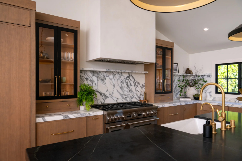 Open concept kitchen - transitional u-shaped light wood floor, brown floor and vaulted ceiling open concept kitchen idea in Orange County with a farmhouse sink, flat-panel cabinets, light wood cabinets, marble countertops, multicolored backsplash, marble backsplash, stainless steel appliances, an island and multicolored countertops