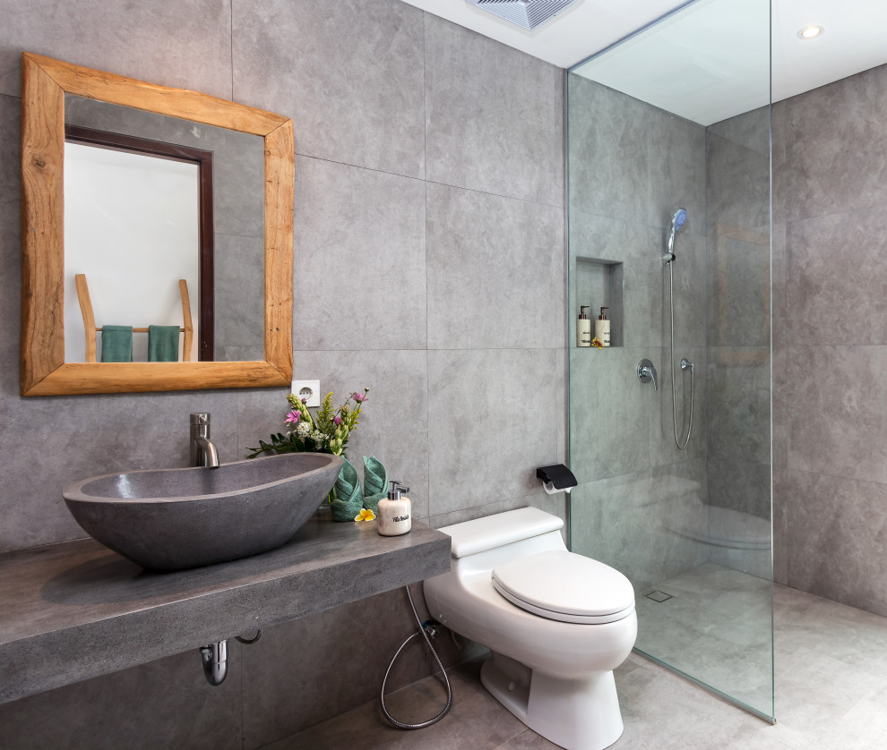 Photo of a tropical bathroom in Other with a curbless shower, gray tile, a vessel sink, grey floor, an open shower, grey benchtops and a single vanity.