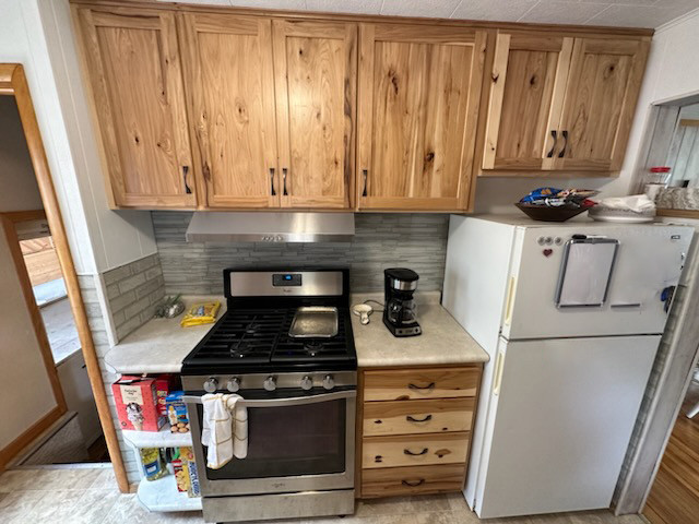 Example of a mid-sized mountain style eat-in kitchen design with shaker cabinets, light wood cabinets and mosaic tile backsplash