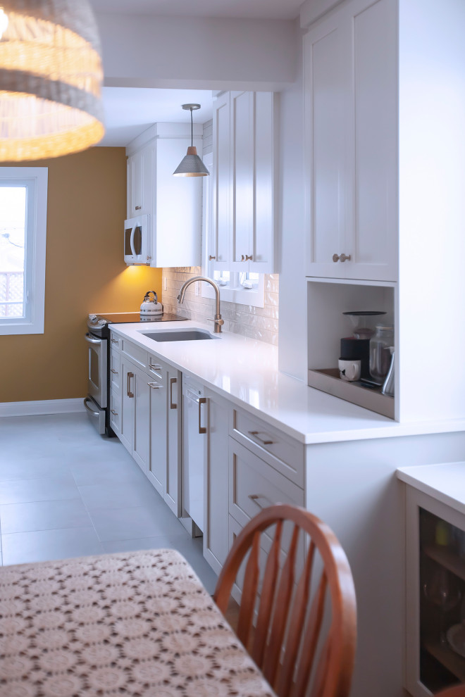 Mid-sized transitional single-wall eat-in kitchen photo with an undermount sink, shaker cabinets, white cabinets, quartz countertops, porcelain backsplash, stainless steel appliances, no island and white countertops