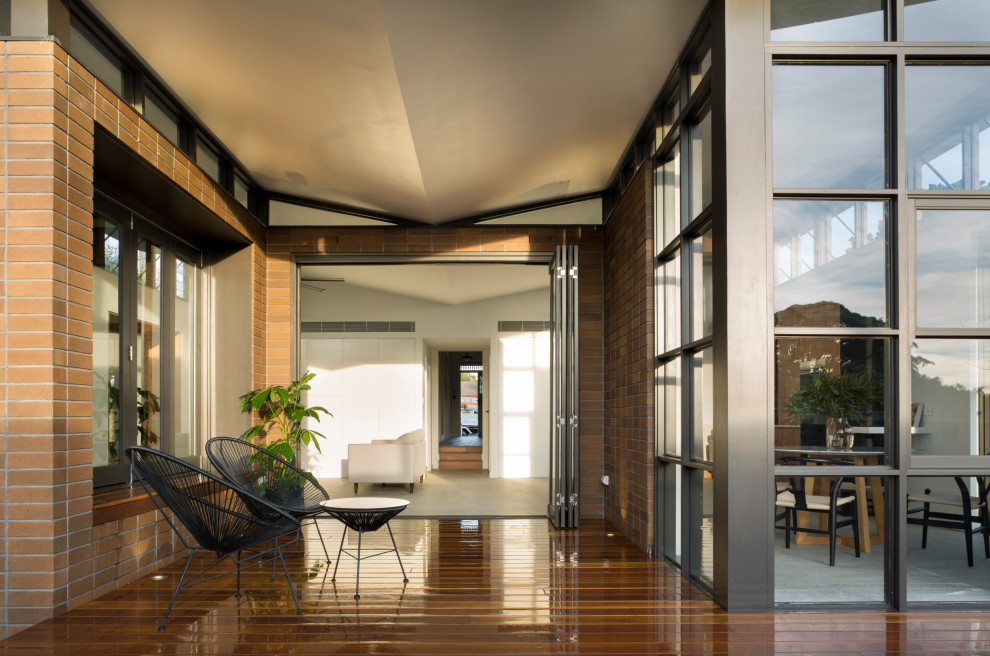 This is an example of a mid-sized contemporary one-storey brick brown house exterior in Sydney with a hip roof and a metal roof.