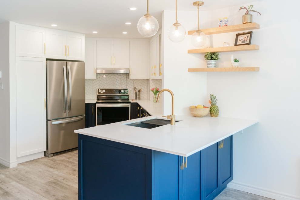 モントリオールにある高級な中くらいなミッドセンチュリースタイルのおしゃれなキッチン (シングルシンク、シェーカースタイル扉のキャビネット、青いキャビネット、クオーツストーンカウンター、白いキッチンパネル、セラミックタイルのキッチンパネル、シルバーの調理設備、ラミネートの床、グレーの床、白いキッチンカウンター) の写真