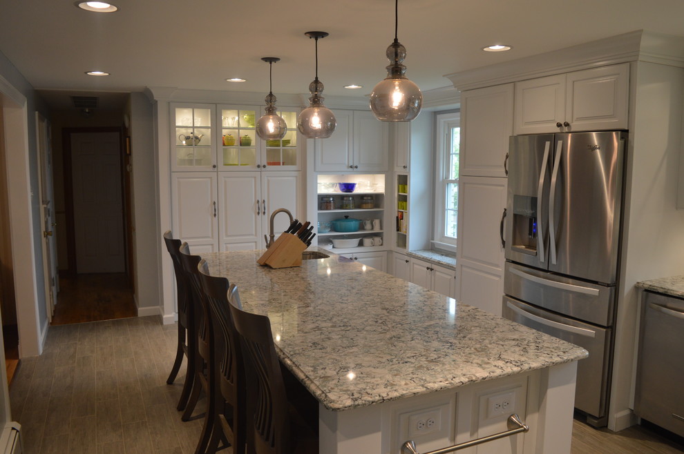 Enclosed kitchen - large transitional u-shaped ceramic tile and gray floor enclosed kitchen idea with a farmhouse sink, raised-panel cabinets, white cabinets, quartz countertops, gray backsplash, glass tile backsplash, stainless steel appliances and an island