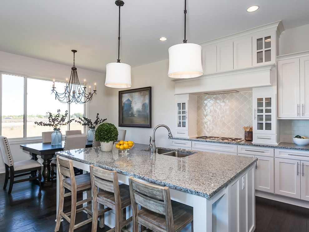 Inspiration for a traditional l-shaped kitchen in Wichita with a double-bowl sink, shaker cabinets, white cabinets, granite benchtops, white splashback, ceramic splashback, stainless steel appliances, dark hardwood floors and with island.