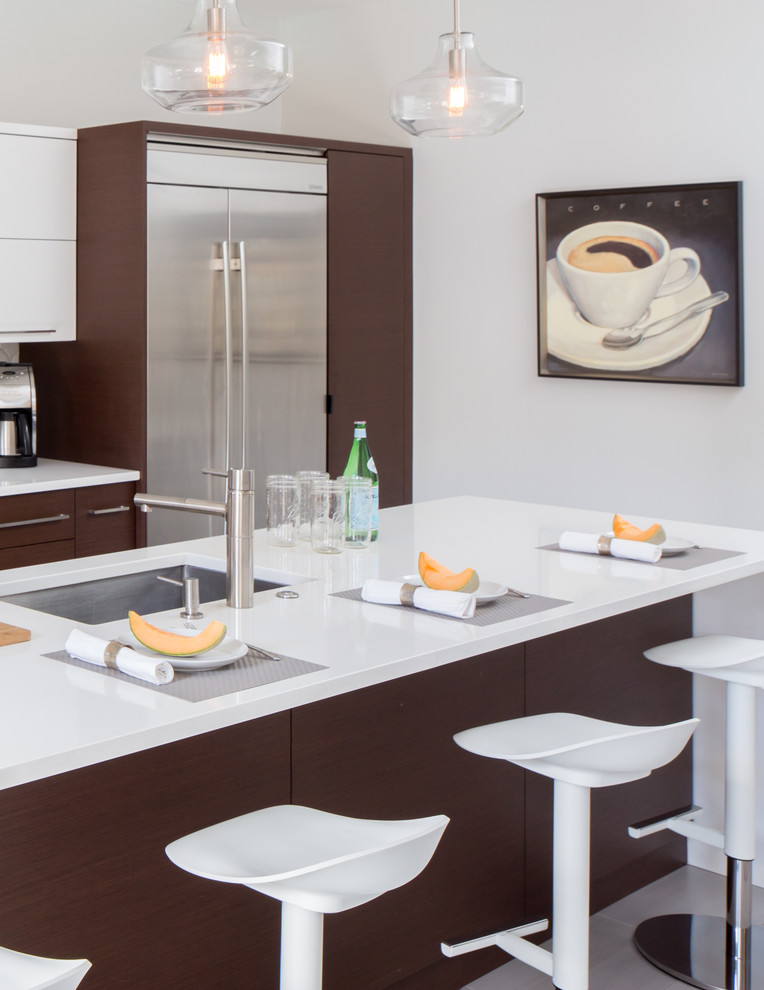 Inspiration for a mid-sized contemporary galley separate kitchen in St Louis with a single-bowl sink, flat-panel cabinets, dark wood cabinets, quartz benchtops, white splashback, ceramic splashback, stainless steel appliances, porcelain floors and with island.
