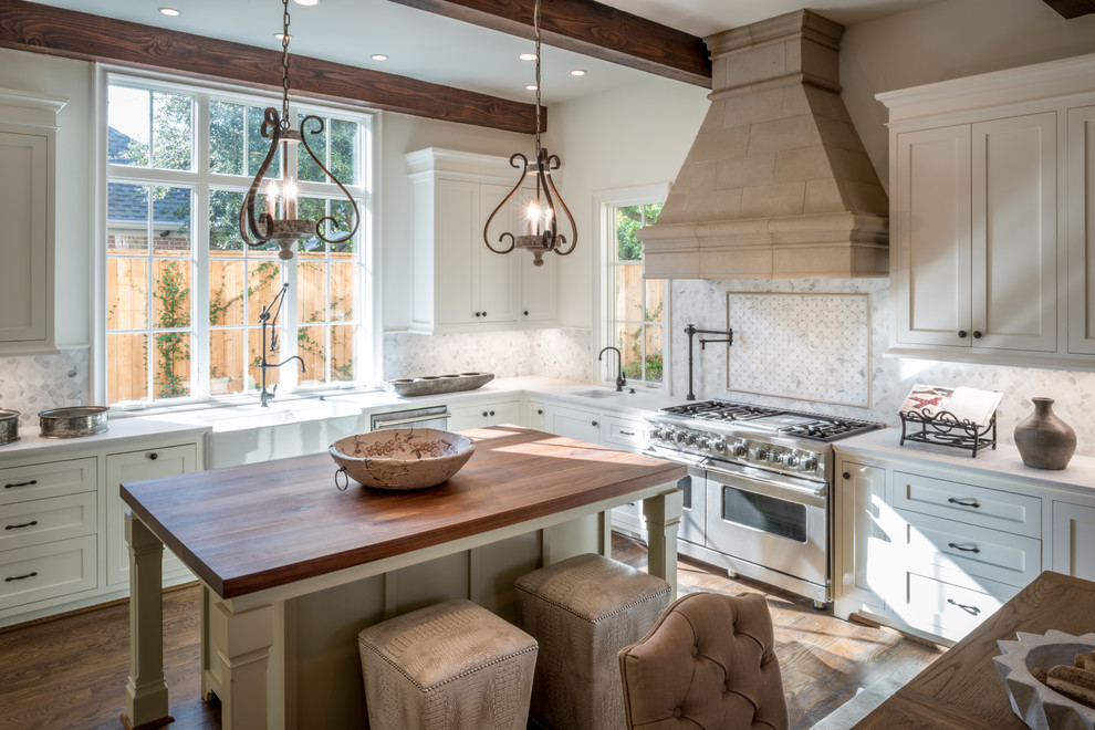 Inspiration for a large l-shaped eat-in kitchen in Houston with a farmhouse sink, white cabinets, white splashback, marble splashback, stainless steel appliances, medium hardwood floors, with island, brown floor, shaker cabinets and white benchtop.