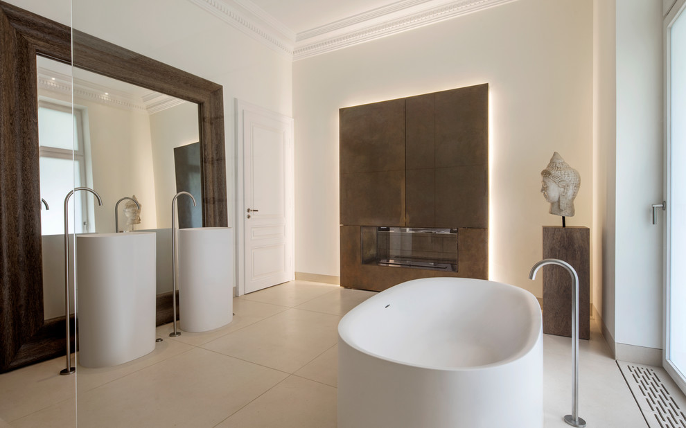 This is an example of a large contemporary master bathroom in Frankfurt with a freestanding tub, brown tile, white walls, a pedestal sink and beige floor.