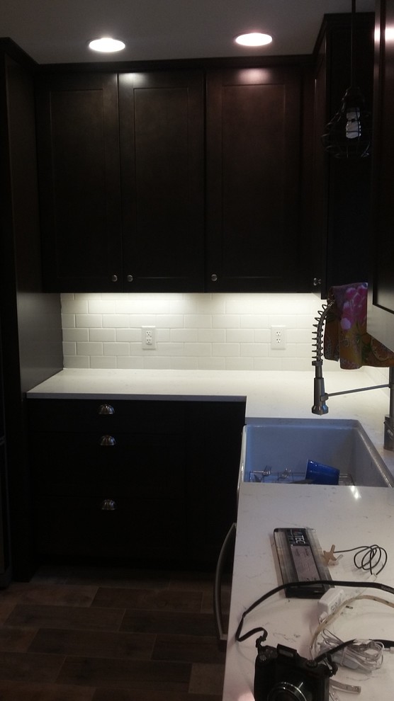 Eat-in kitchen - mid-sized rustic u-shaped porcelain tile eat-in kitchen idea in Indianapolis with a farmhouse sink, shaker cabinets, dark wood cabinets, wood countertops, white backsplash, ceramic backsplash, stainless steel appliances and an island
