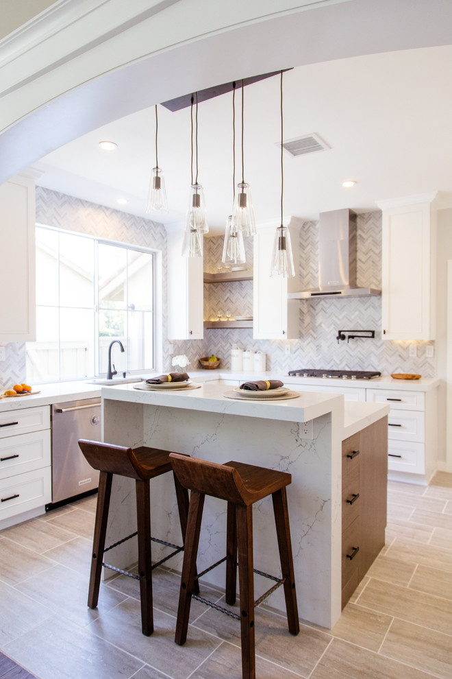 Photo of a mid-sized contemporary l-shaped eat-in kitchen in Orange County with an undermount sink, shaker cabinets, white cabinets, marble benchtops, grey splashback, porcelain floors, with island, mosaic tile splashback, stainless steel appliances and grey floor.