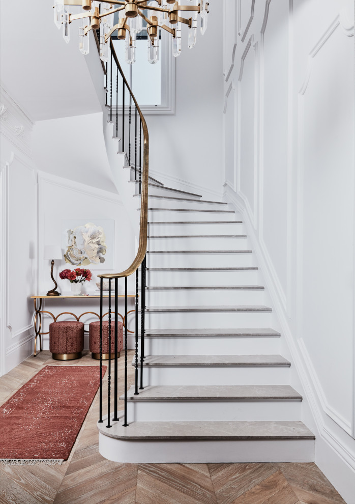 This is an example of a large transitional marble curved staircase in Sydney with painted wood risers, metal railing and decorative wall panelling.