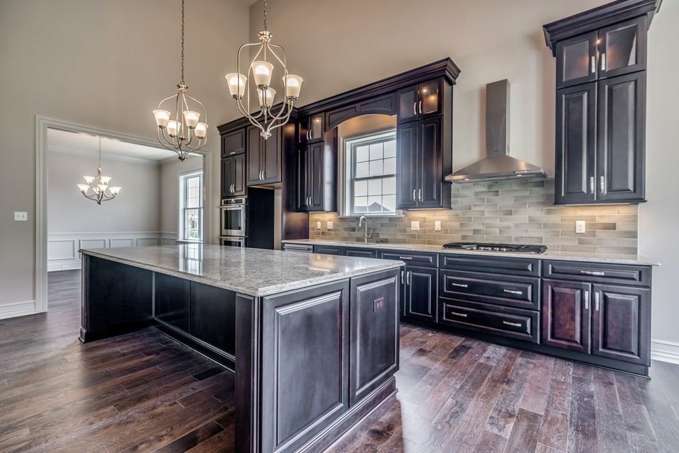 Eat-in kitchen - large transitional single-wall dark wood floor and brown floor eat-in kitchen idea with an undermount sink, raised-panel cabinets, brown cabinets, quartz countertops, beige backsplash, subway tile backsplash, stainless steel appliances, an island and beige countertops