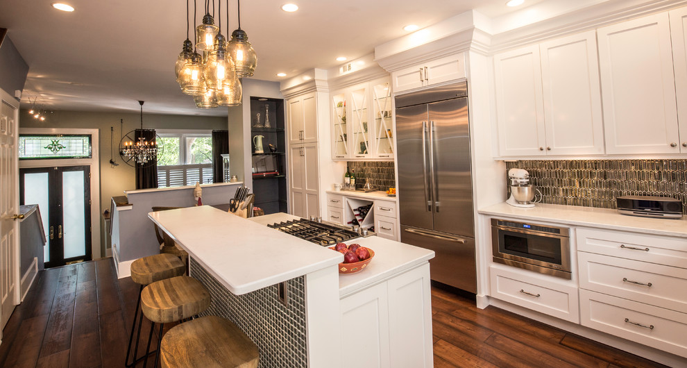 Photo of a mid-sized eclectic l-shaped eat-in kitchen in Philadelphia with an undermount sink, shaker cabinets, quartz benchtops, grey splashback, glass tile splashback, stainless steel appliances, dark hardwood floors, with island, brown floor and white cabinets.