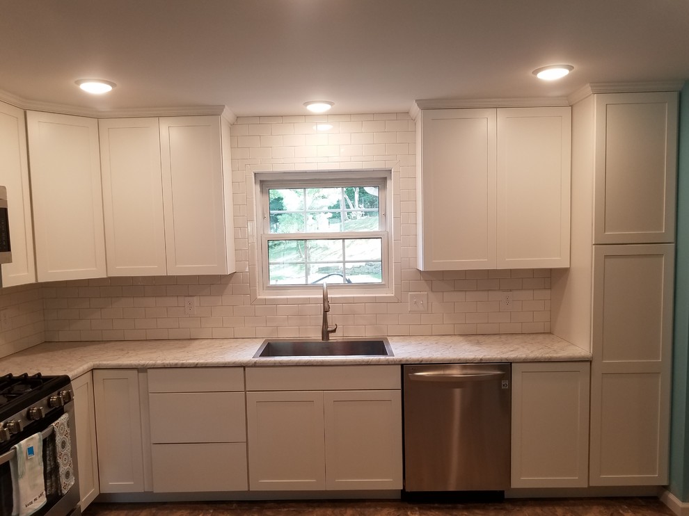 Example of a mid-sized transitional l-shaped vinyl floor and beige floor eat-in kitchen design in Cincinnati with a single-bowl sink, shaker cabinets, white cabinets, laminate countertops, white backsplash, porcelain backsplash, stainless steel appliances and no island