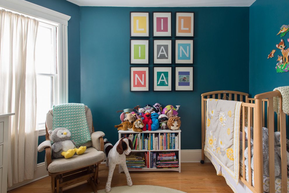 Transitional gender-neutral nursery in Boston with medium hardwood floors, blue walls and beige floor.