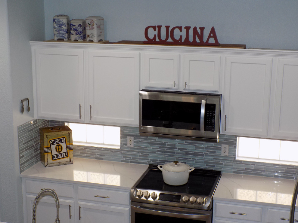 Small contemporary u-shaped kitchen in Denver with an undermount sink, recessed-panel cabinets, white cabinets, quartzite benchtops, blue splashback, glass tile splashback, stainless steel appliances, painted wood floors, with island, yellow floor and white benchtop.