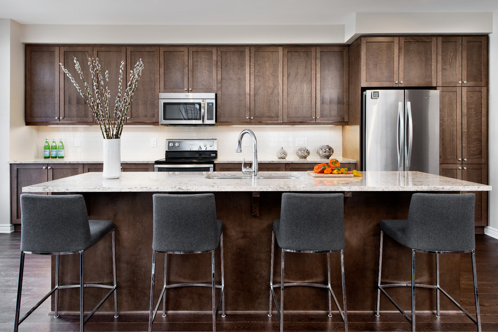 Transitional dark wood floor kitchen photo in Ottawa with an undermount sink, shaker cabinets, dark wood cabinets, white backsplash, subway tile backsplash, stainless steel appliances and an island