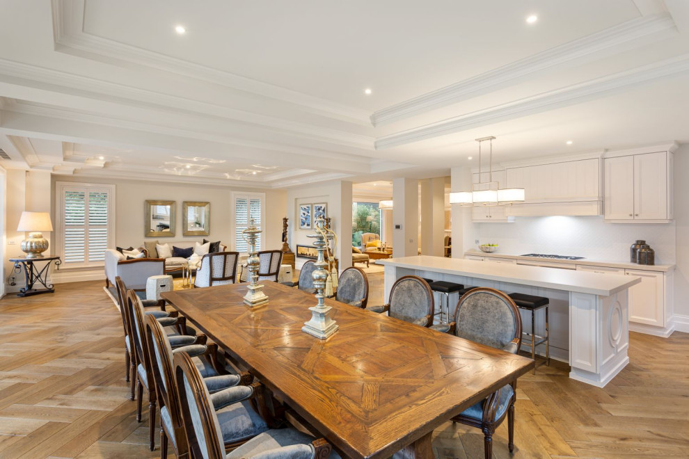 This is an example of an expansive traditional open plan kitchen in Melbourne with an undermount sink, shaker cabinets, white cabinets, marble benchtops, white splashback, subway tile splashback, stainless steel appliances, medium hardwood floors, with island, brown floor and white benchtop.