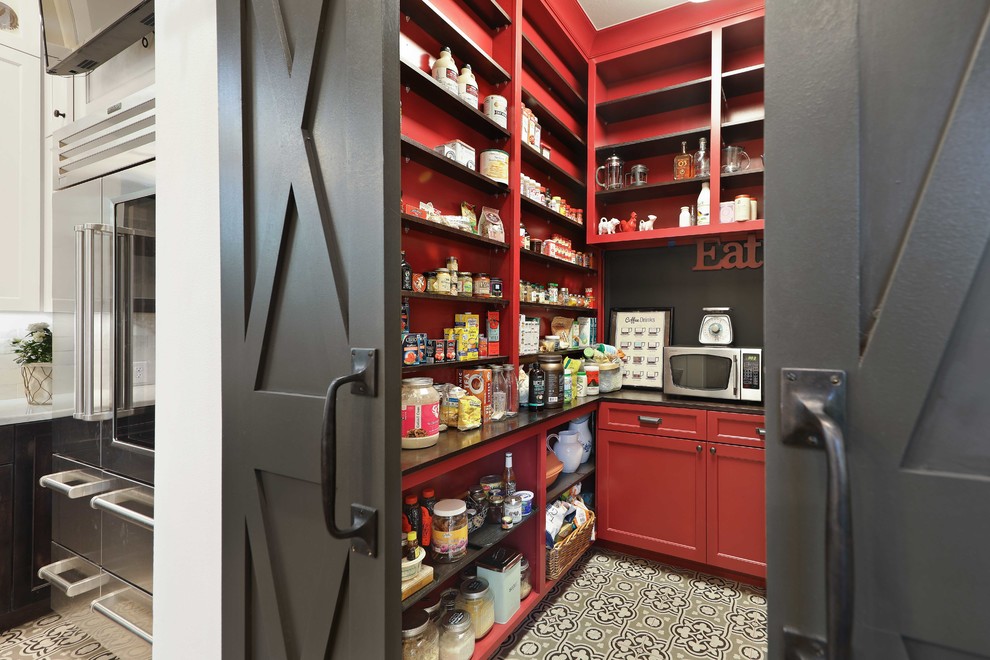 This is an example of a country u-shaped kitchen pantry in Austin with red cabinets, cement tiles, no island, multi-coloured floor, black benchtop and open cabinets.