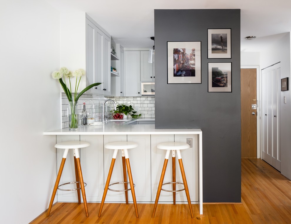 Small contemporary u-shaped kitchen in Vancouver with an undermount sink, shaker cabinets, grey cabinets, quartz benchtops, white splashback, subway tile splashback, stainless steel appliances, black floor and white benchtop.
