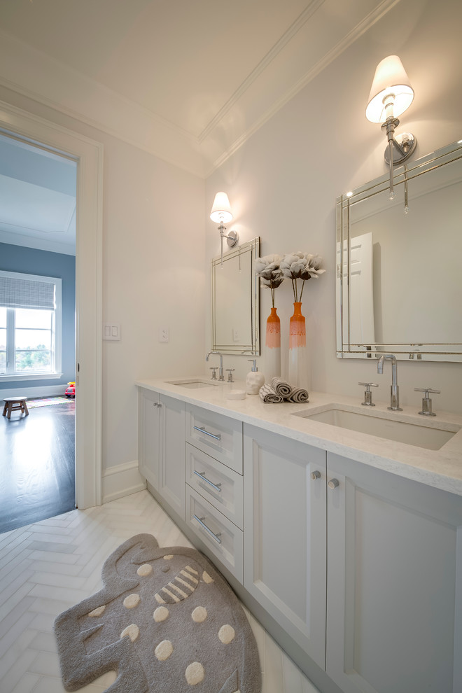 Mid-sized modern kids bathroom in Toronto with an undermount sink, recessed-panel cabinets, grey cabinets, engineered quartz benchtops, a drop-in tub, a one-piece toilet, gray tile, stone tile, grey walls and medium hardwood floors.