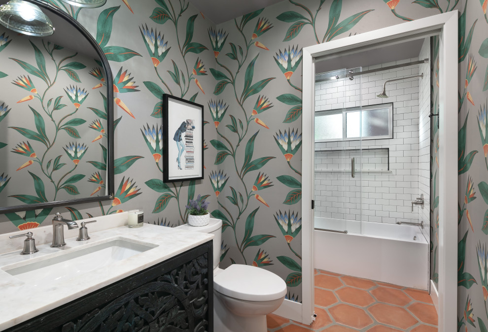 Inspiration for a medium sized traditional family bathroom in Los Angeles with freestanding cabinets, black cabinets, an alcove bath, a shower/bath combination, a one-piece toilet, white tiles, metro tiles, multi-coloured walls, terracotta flooring, a submerged sink, marble worktops, brown floors, a sliding door, white worktops, a wall niche, a single sink, a freestanding vanity unit and wallpapered walls.