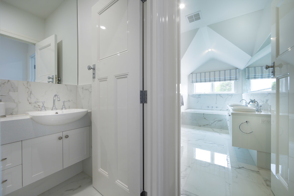 Design ideas for a transitional bathroom in Melbourne with a drop-in tub, ceramic tile, white walls and marble floors.