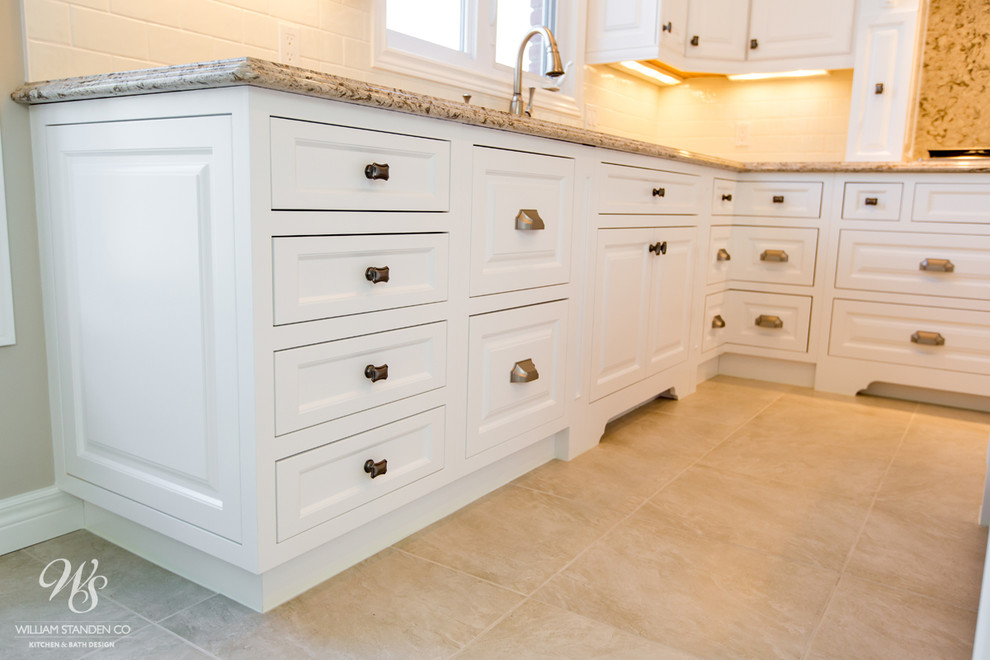Example of a mid-sized transitional u-shaped porcelain tile eat-in kitchen design in Toronto with an undermount sink, raised-panel cabinets, white cabinets, quartzite countertops, beige backsplash, stone slab backsplash, stainless steel appliances and an island