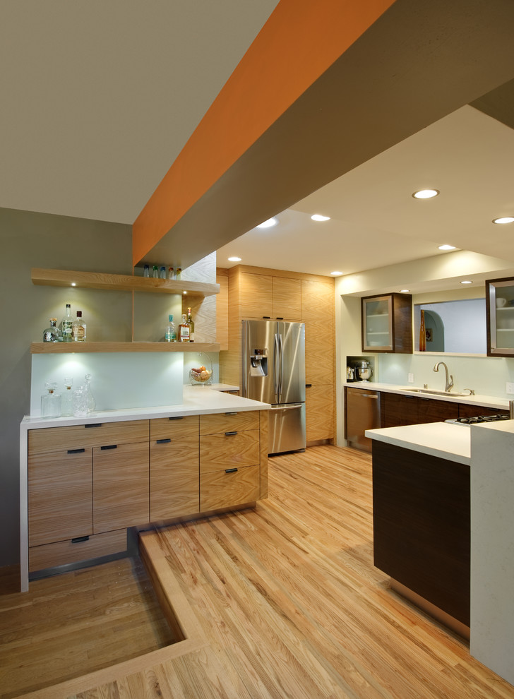 Design ideas for a large contemporary u-shaped eat-in kitchen in Albuquerque with an undermount sink, flat-panel cabinets, light wood cabinets, quartz benchtops, white splashback, glass sheet splashback, stainless steel appliances, medium hardwood floors and a peninsula.