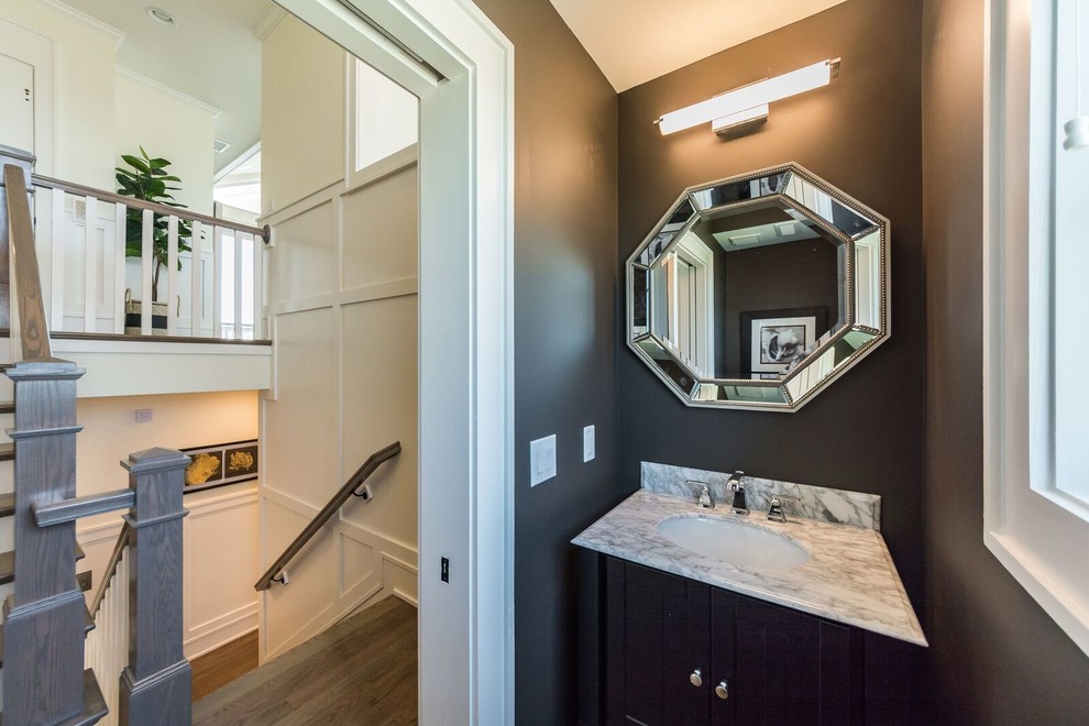This is an example of a small transitional powder room in Other with shaker cabinets, black cabinets, black walls, dark hardwood floors, an undermount sink, marble benchtops, brown floor and white benchtops.