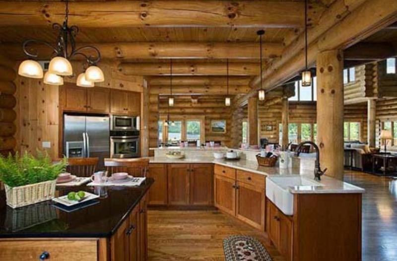 Example of a mountain style medium tone wood floor open concept kitchen design with a farmhouse sink, shaker cabinets, medium tone wood cabinets, quartz countertops, stainless steel appliances and an island