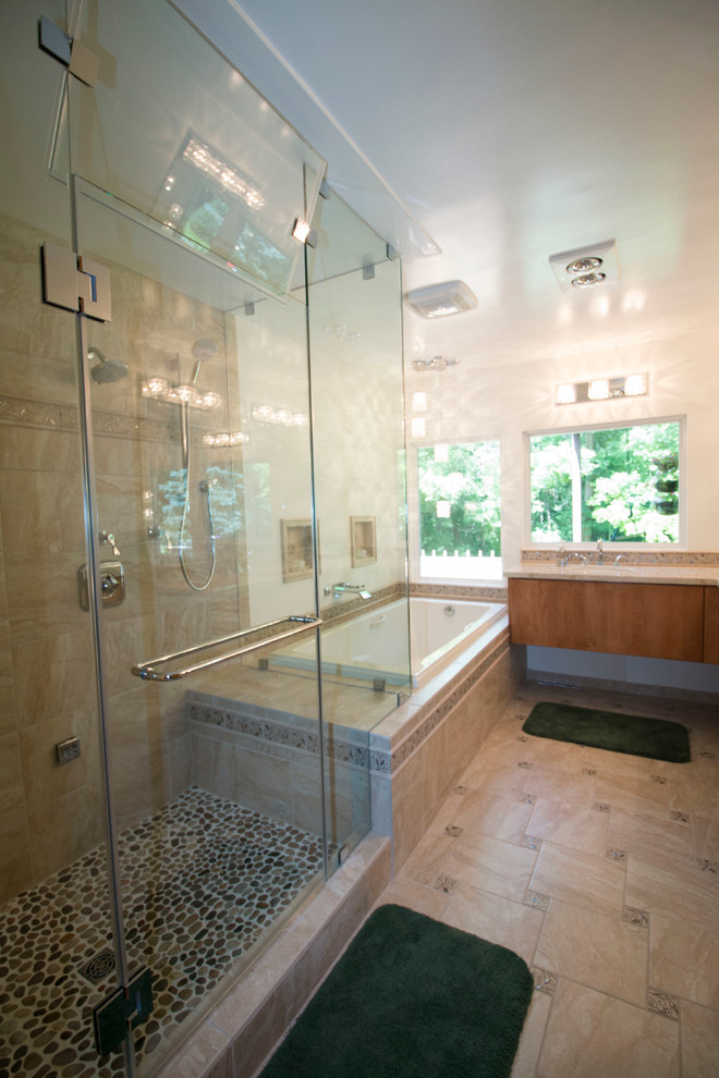 Inspiration for a mid-sized transitional master beige tile and ceramic tile ceramic tile drop-in bathtub remodel with an undermount sink, flat-panel cabinets, light wood cabinets, solid surface countertops, a two-piece toilet and beige walls