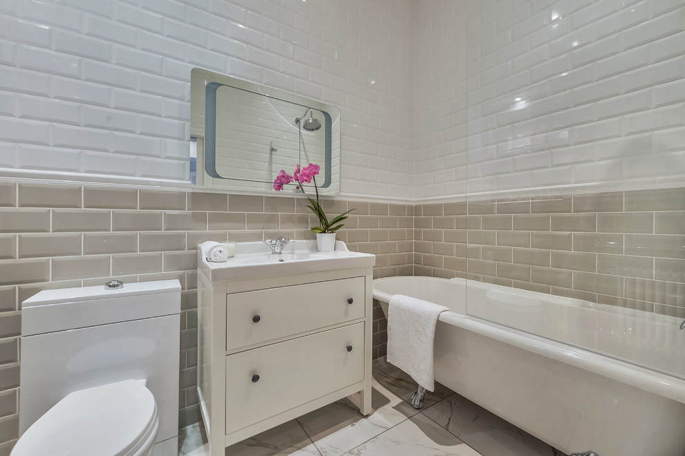 Inspiration for a transitional bathroom in London with white cabinets, a claw-foot tub, a shower/bathtub combo, gray tile, subway tile, a console sink and flat-panel cabinets.