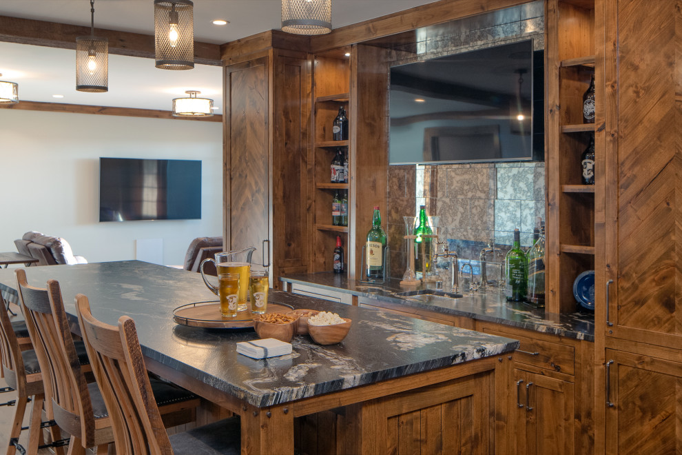 Country seated home bar in Minneapolis with an undermount sink, shaker cabinets, medium wood cabinets, mirror splashback and multi-coloured benchtop.