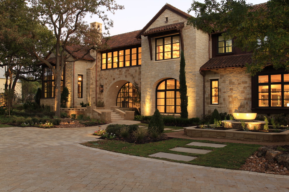 Photo of a mediterranean two-storey beige exterior in Dallas with stone veneer and a gable roof.