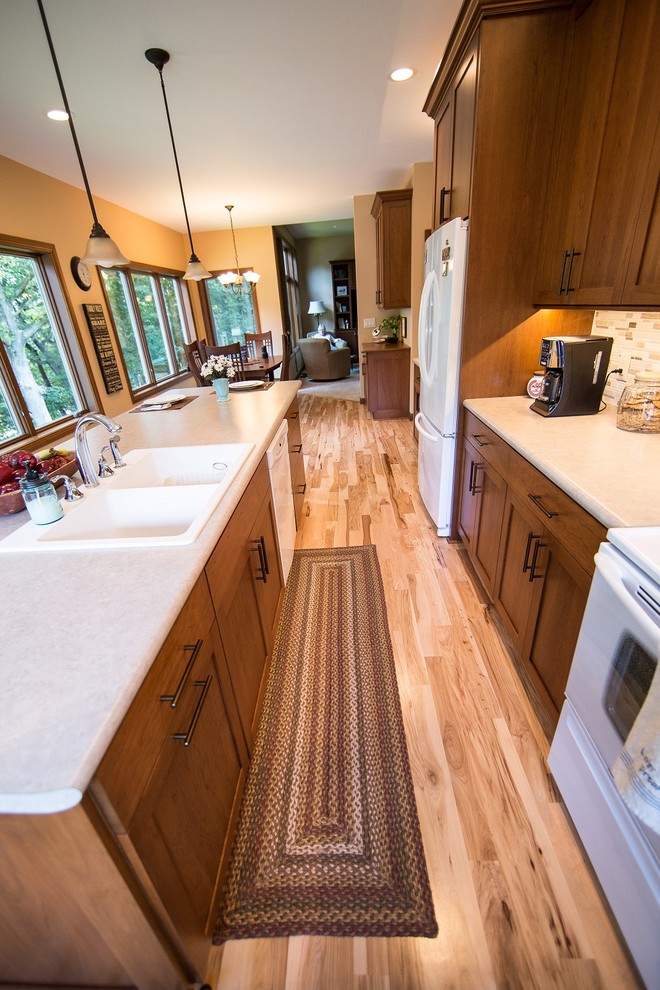 Large transitional l-shaped light wood floor eat-in kitchen photo in Cedar Rapids with a double-bowl sink, recessed-panel cabinets, medium tone wood cabinets, laminate countertops, multicolored backsplash, mosaic tile backsplash, white appliances and an island